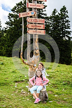 Children in frontÂ Wooden Signpost on Velika Planina in Slovenia